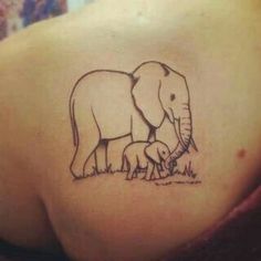 an elephant tattoo on the back of a woman's shoulder