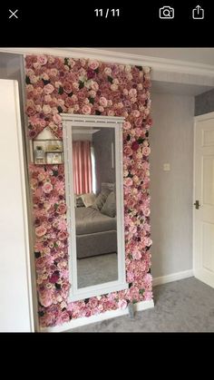 a large mirror sitting on top of a wall covered in pink and white flowers next to a couch