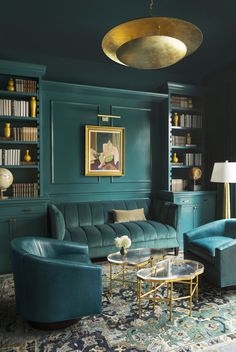 a living room with green walls and blue couches in the corner, gold accents