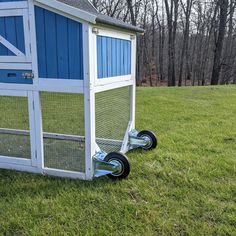 a blue and white chicken coop sitting in the grass