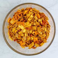 a glass bowl filled with cereal and pretzels on top of a white counter