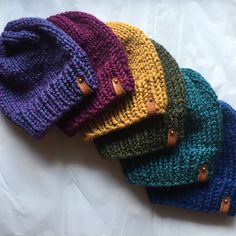 five knit beanies are lined up on a white sheet