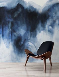 a chair sitting in front of a wall painted with blue and black watercolors