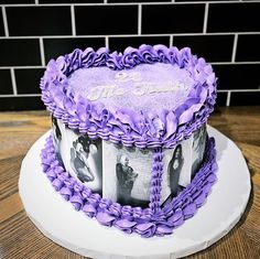 a purple cake with pictures on it sitting on a table next to a brick wall