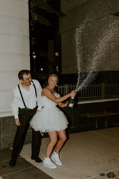 a man and woman in tutus are holding champagne