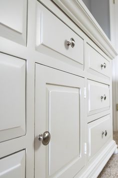 a white dresser with drawers and knobs in a room