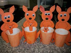 an orange paper cup with five kangaroos in it and one is holding a baby