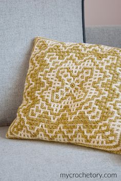 a yellow and white pillow sitting on top of a gray couch