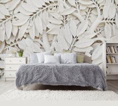 a bedroom with a bed, bookshelf and wallpaper that has leaves on it