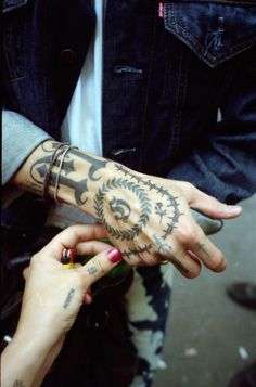 two people with tattoos on their hands and one is holding the other's hand