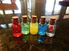 six small bottles filled with different colored confetti on top of a countertop