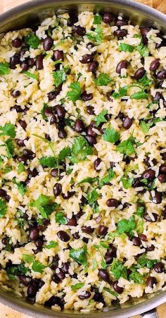 black beans and rice in a pan on a wooden table with spoons next to it