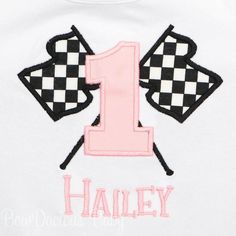 a white shirt with pink and black checkered number one on the front, embroidered onto it