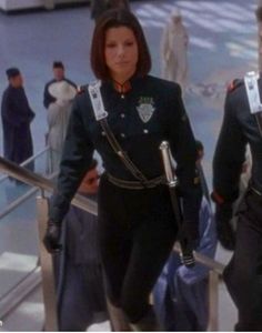 two women in black uniforms walking down an escalator