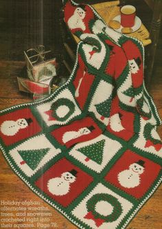 a crocheted christmas afghan with santas and snowmen on it, sitting on a wooden floor