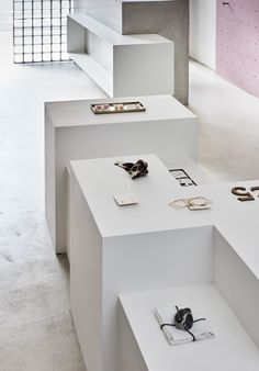 several white shelves with various pairs of shoes on them in a room that has pink and white walls