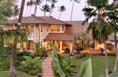 a house with palm trees in the front yard and walkway leading up to it's entrance