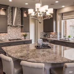 a large kitchen with marble counter tops and dark wood cabinets, along with white chairs