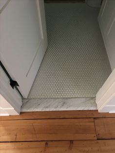 an empty bathroom with wood flooring and white tile on the shower wall, next to a door