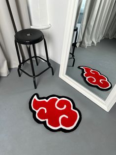 a mirror sitting next to a stool in front of a chair with a red and black design on it