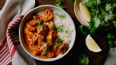 a white bowl filled with chicken and rice next to cilantro, lime wedges and lemon wedges