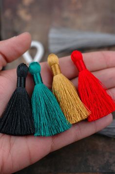 three tassels in the palm of someone's hand, one red and one green