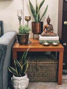 a buddha statue sitting on top of a wooden table next to a potted plant