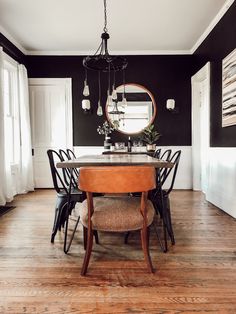 a dining room with black walls and wooden flooring is pictured in this image, there are four chairs around the table