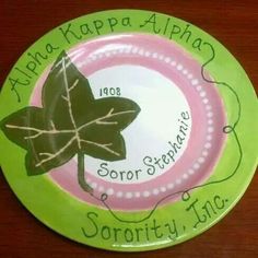 a green and pink plate with an image of a leaf on it's side