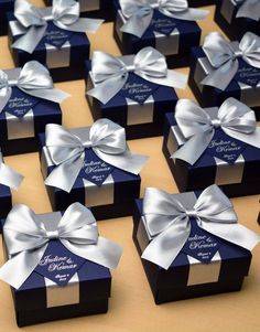 many small boxes with bows on them are sitting on a table together, one is blue and the other is silver