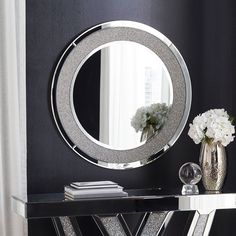 a black and white room with a round mirror on the wall above a console table