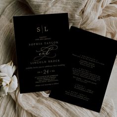 an elegant black and white wedding suite on top of a bed next to a flower