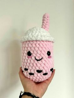 a hand holding up a crocheted cup with a face on it