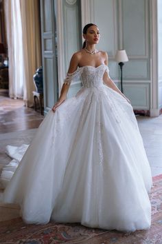 a woman in a white wedding dress standing on the floor with her hands on her hips