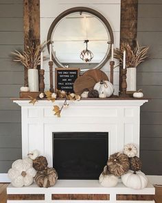 a white fireplace with pumpkins and candles on it