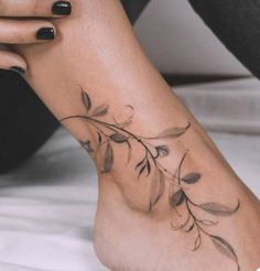 a woman's foot with flowers on it and her hand resting on the ground