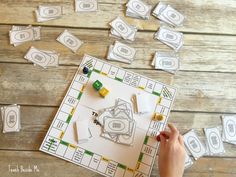 a person is playing monopoly on a wooden table with dices and pieces of paper