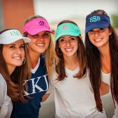 four young women are posing for the camera with their hats on and one is wearing a white t - shirt