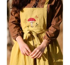 a woman in a yellow dress is holding her hands out to the side with a mushroom on it