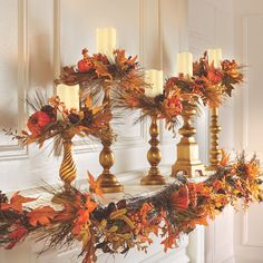 a mantle decorated with candles and fall leaves