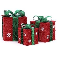 three red boxes with green bows and snowflakes on them, all wrapped in sequins