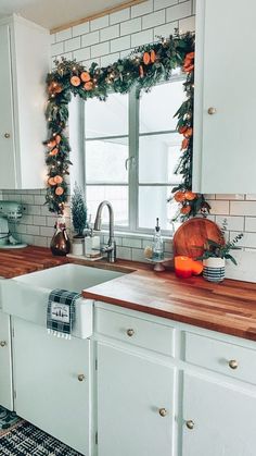 a kitchen decorated for christmas with garland on the window