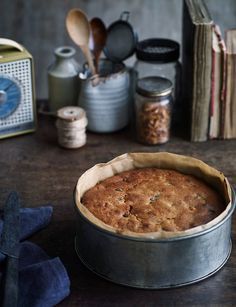 a cake in a tin sitting on a table next to some books and other kitchen utensils