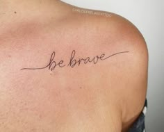 the back of a man's shoulder that says be brave in cursive writing