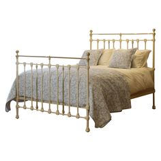 a metal bed frame with two pillows on top of it and a blanket over the headboard