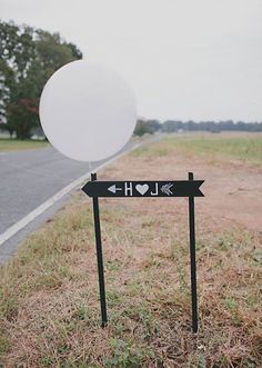 a sign that is sitting in the grass with a balloon attached to it's post