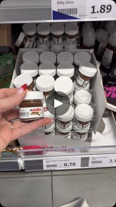 a person is holding up some food in front of the store display shelf and pointing at it