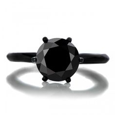 a black diamond ring sitting on top of a white table next to an iphone screen