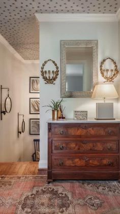 a room with a dresser, mirror and pictures on the wall above it is shown