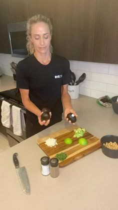 a woman standing in front of a cutting board with some food on top of it